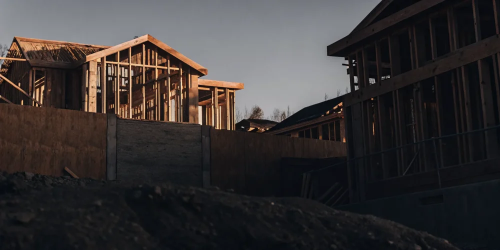 Modern custom home under construction with wooden framing against blue sky