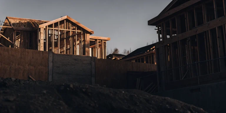 Modern custom home under construction with wooden framing against blue sky