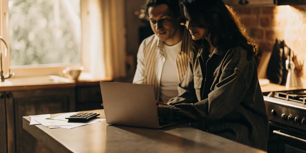 A couple reviewing rent versus buy calculations on a laptop at their kitchen table
